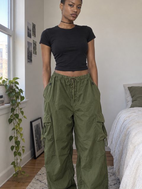 Olive baggy cargo pants with a drawstring waist, worn and shot at home, hands free
